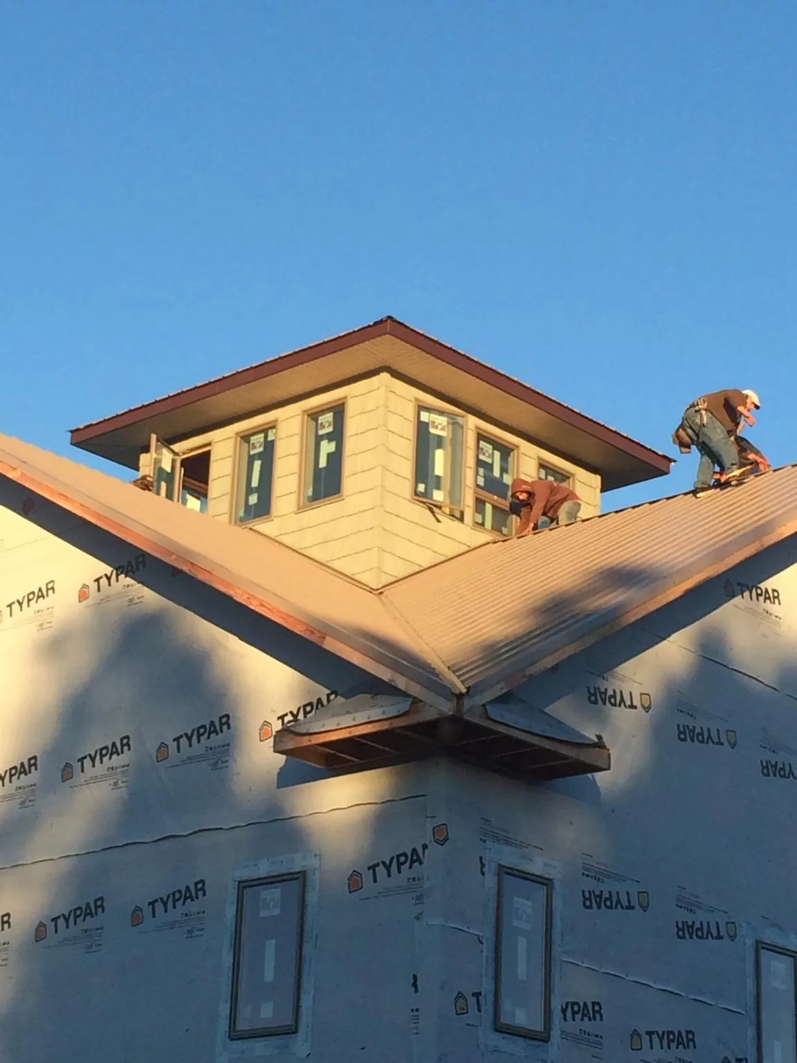 Roofers working around a rooftop cupola on a new metal roof at sunset — Roof Waterproofing in Frankfort by Roofing Brothers